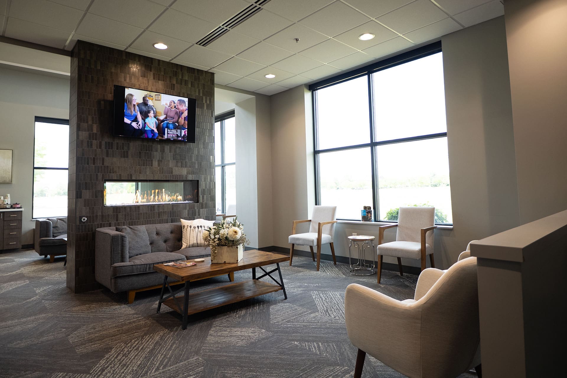 Village Dental at Saxony cozy waiting room with a fireplace, wall-mounted TV, and comfortable seating in Fishers, IN