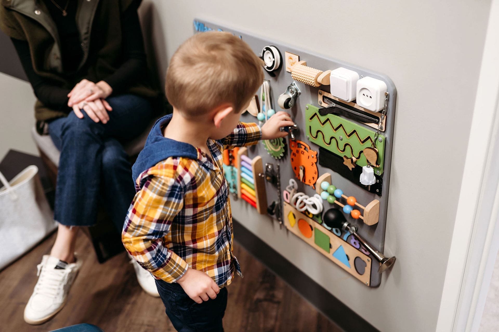 Child exploring an interactive activity wall in the Village Dental at Saxony waiting area in Fishers, IN